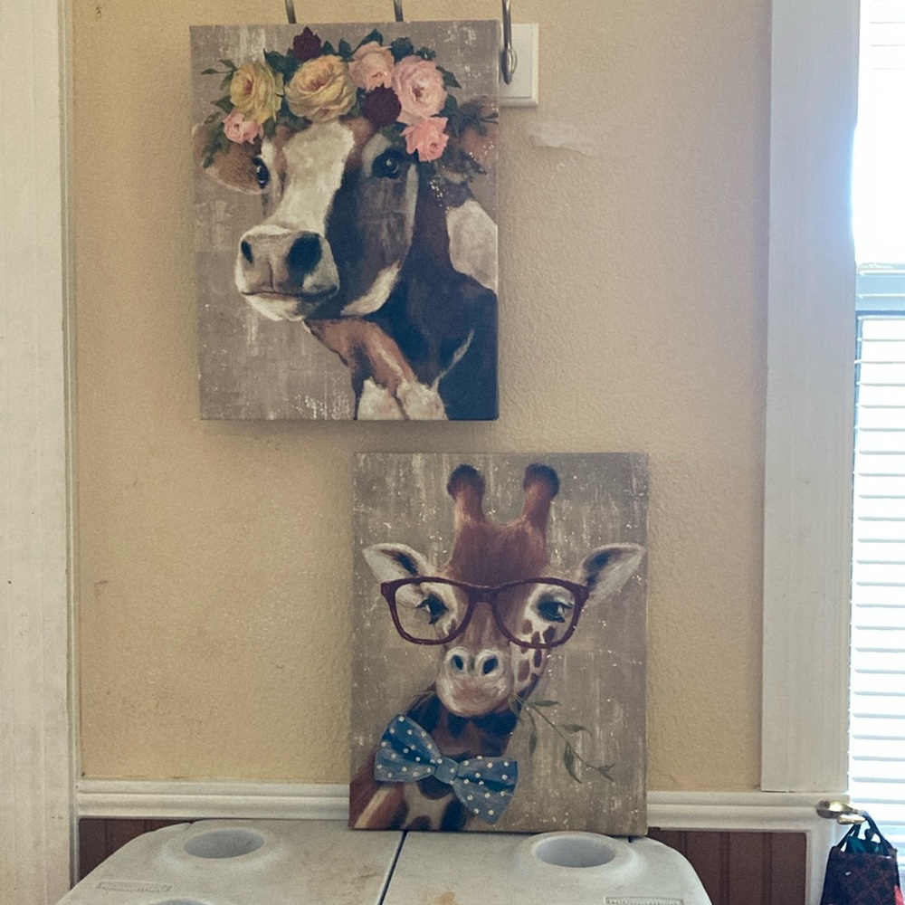 Duo of animal paintings a cow, wearing flowers, and a giraffe wearing glasses